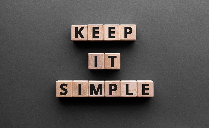 Wooden blocks on a black tabletop that spell out "KEEP IT SIMPLE."