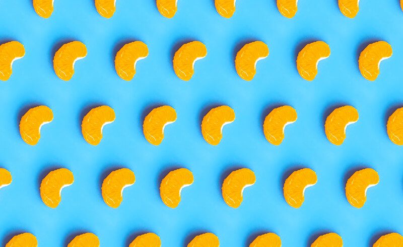 Repeating pattern of mandarin orange slices on a bright blue background.