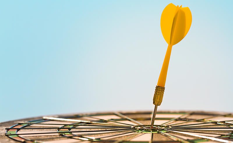 Close-up of a yellow dart stuck in the center of a target.