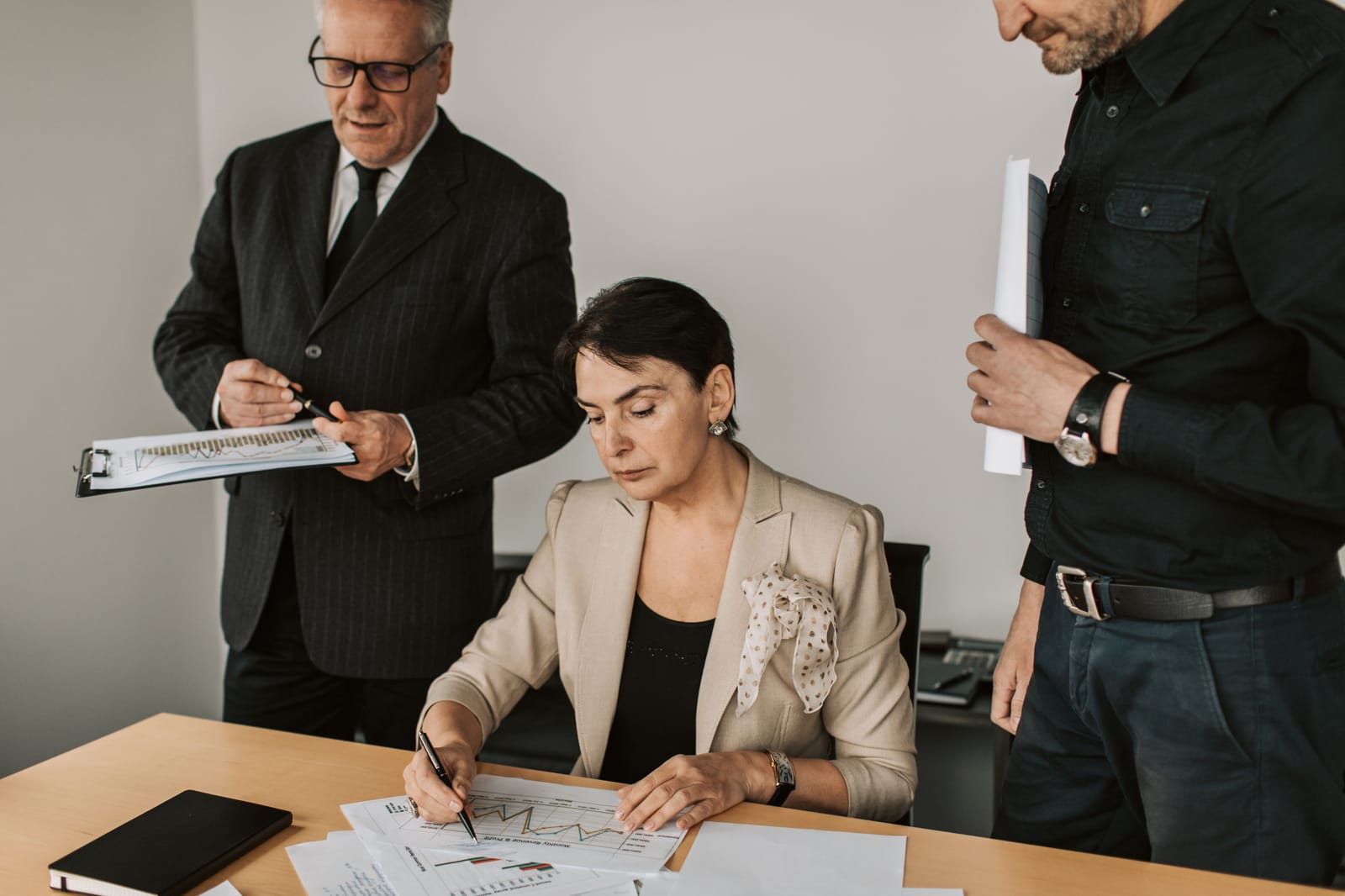 A senior man reviewing work with a colleague at her desk