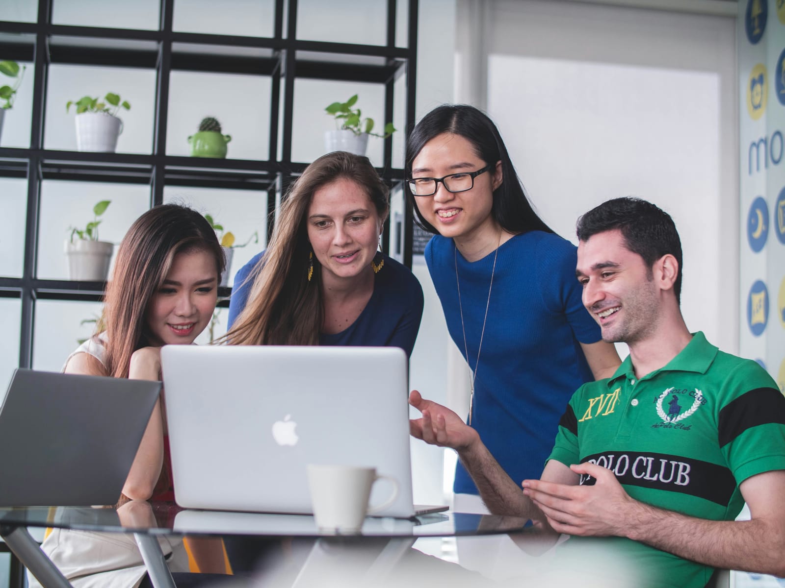 A diverse team smiling around a laptop
